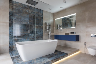 modernes Badezimmer mit großformatigen Fliesen in beige und blau marmoriert und mit einer im Raum stehender Badewanne