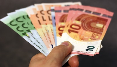 Männerhand die zehn und zwanzig und fünfzig und hundert Euro Geldscheine vor schwarzem Hintergrunf vorzeigt