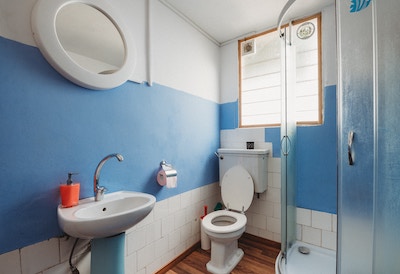 veraltestes Bad mit hellblauen Wänden und braunen Fliesen